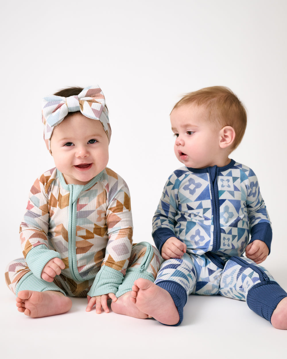 Two newborns wearing Kaleidoscope Dreams and Patchwork Indigo Zippies