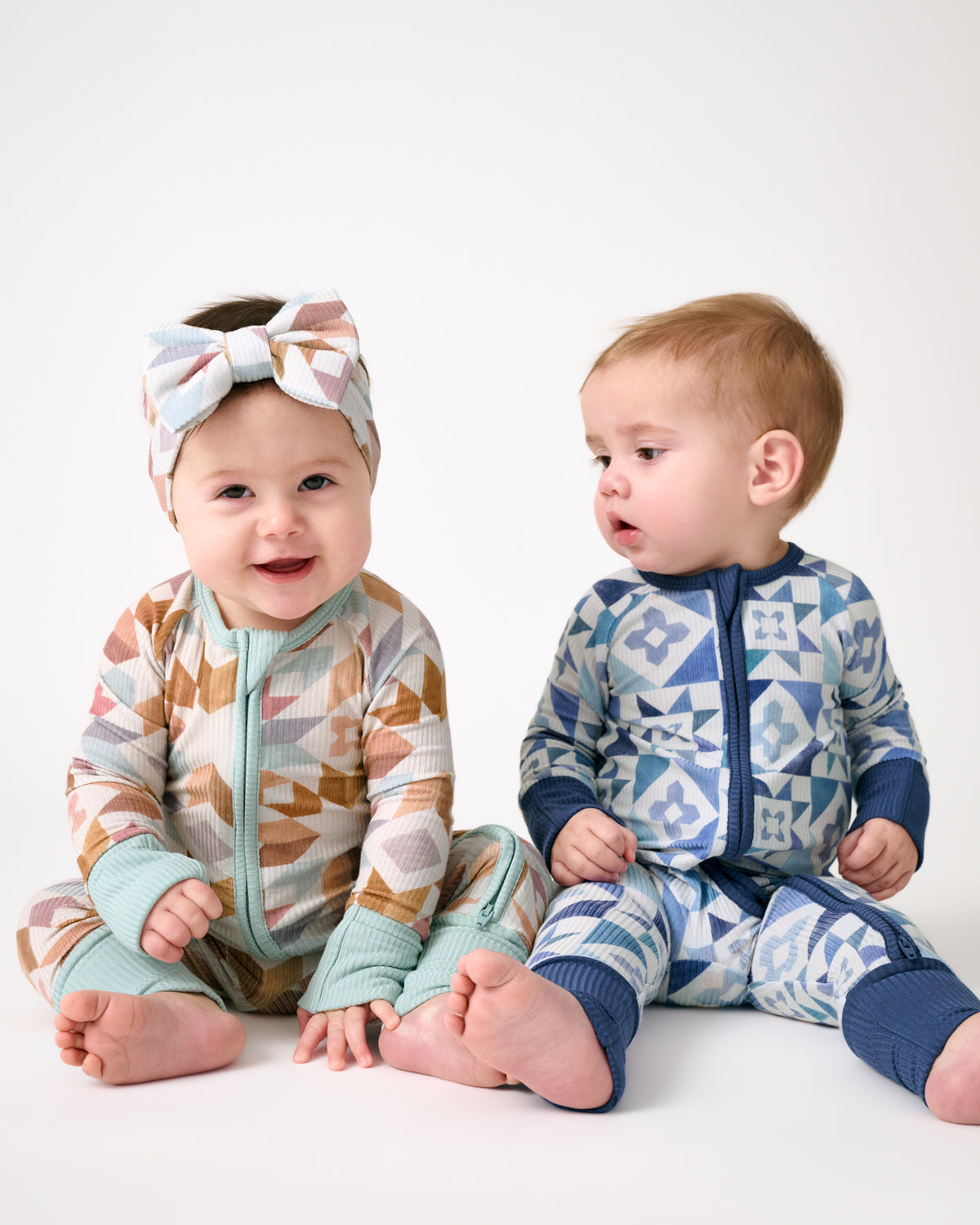Two newborns wearing Kaleidoscope Dreams and Patchwork Indigo Zippies