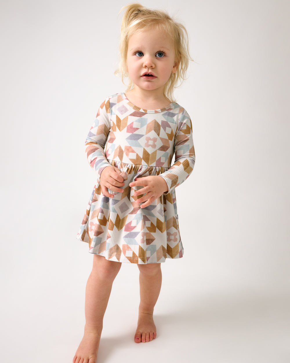 Standing toddler wearing the Kaleidoscope Dreams Ribbed Skater Dress with Bodysuit