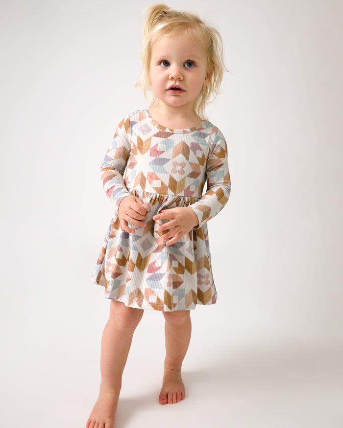 Standing toddler wearing the Kaleidoscope Dreams Ribbed Skater Dress with Bodysuit