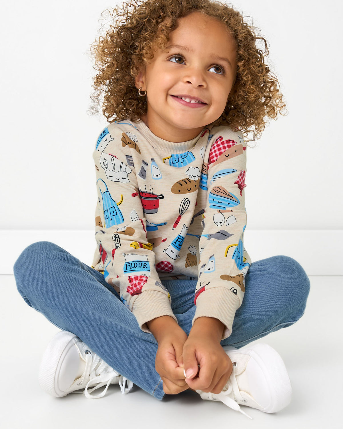 Sitting child wearing the Little Chef Crewneck Sweatshirt with blue deim pants