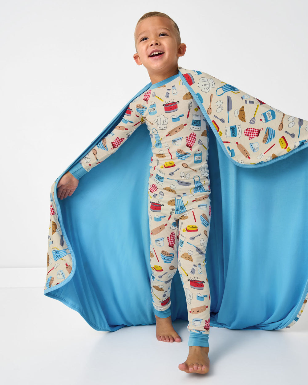 Boy holding up the Little Chef Large Cloud Blanket® showing the solid blue side