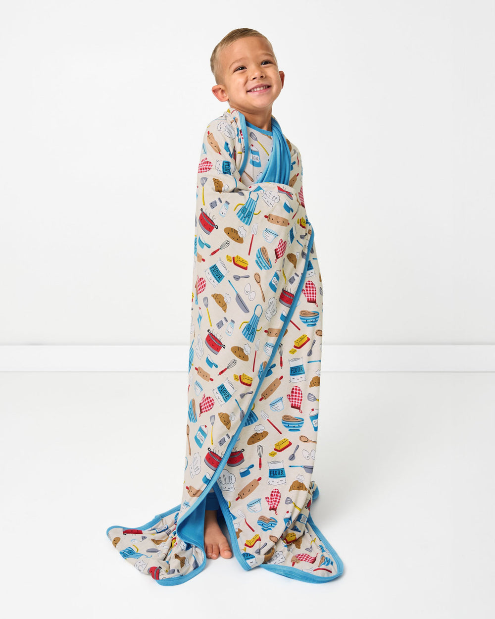 Standing boy wrapped in the Little Chef Large Cloud Blanket®
