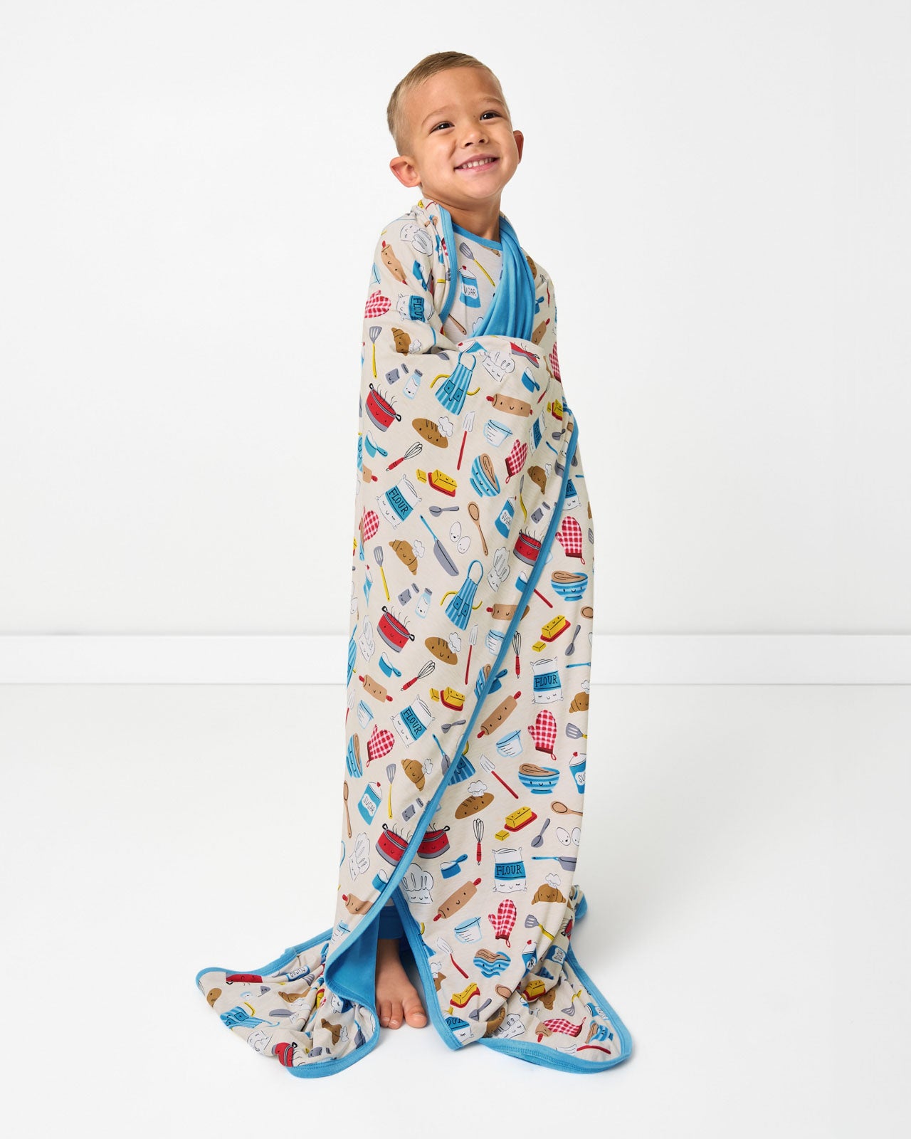 Standing boy wrapped in the Little Chef Large Cloud Blanket®