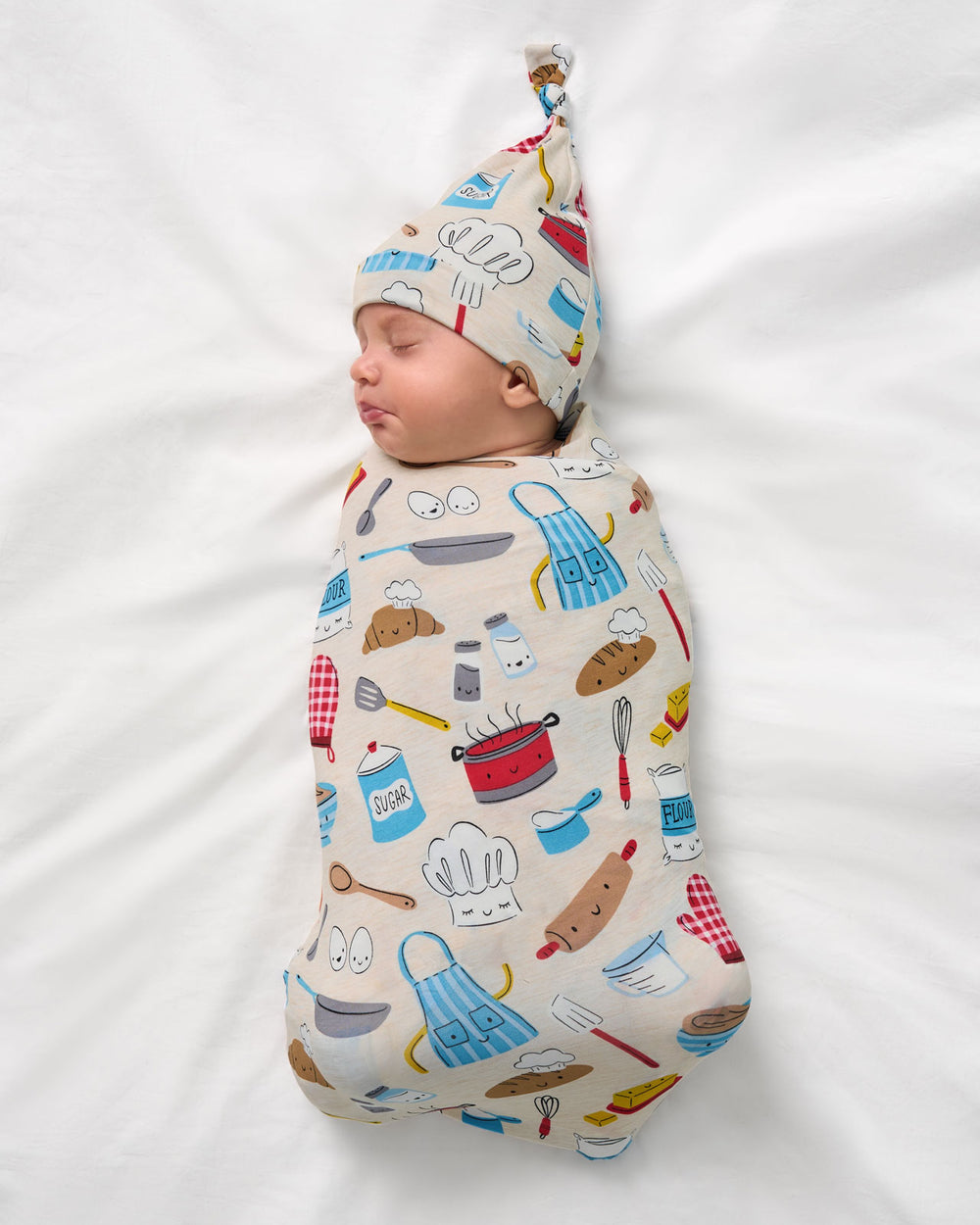 Aerial view of baby wearing the Little Chef Swaddle & Hat Set