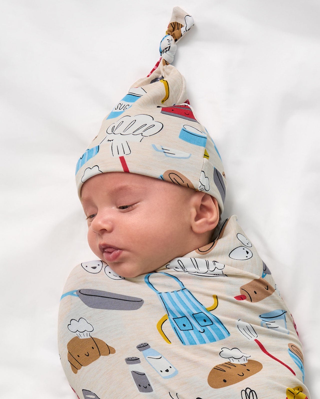 Close up of baby swaddled in the Little Chef Swaddle & Hat Set