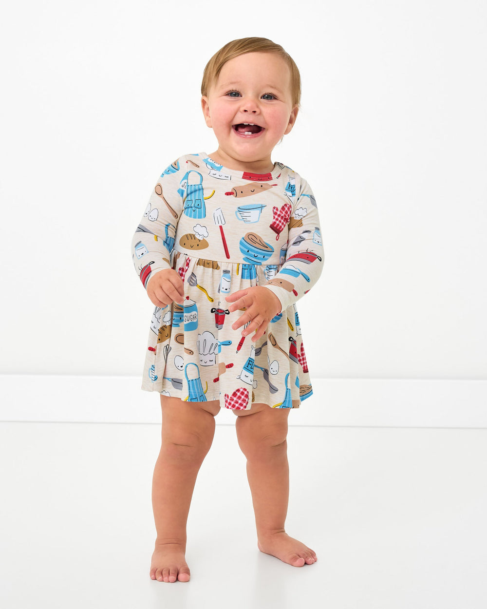 Standing child wearing the Little Chef Twirl Dress with Bodysuit