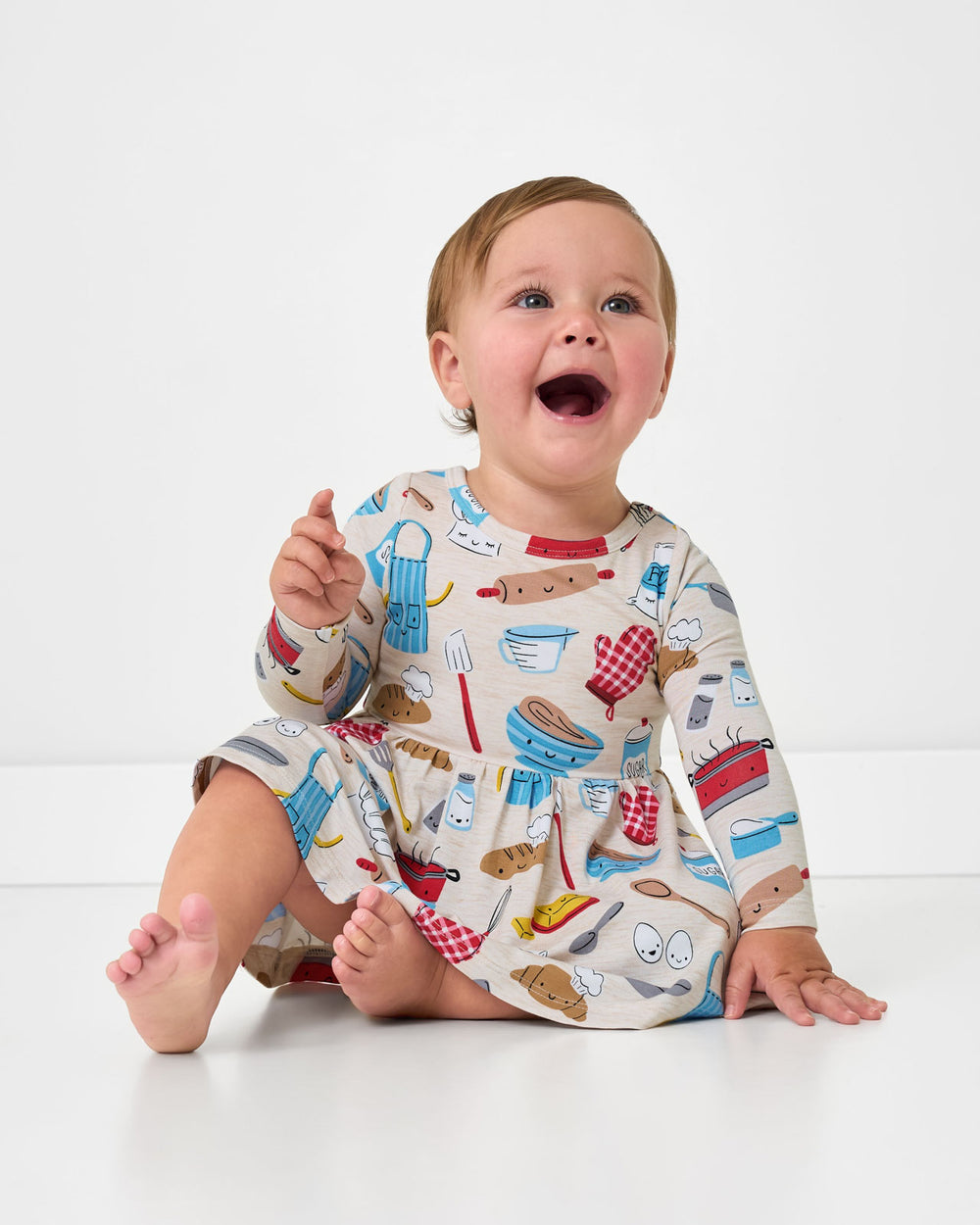 Sitting baby wearing the Little Chef Twirl Dress with Bodysuit