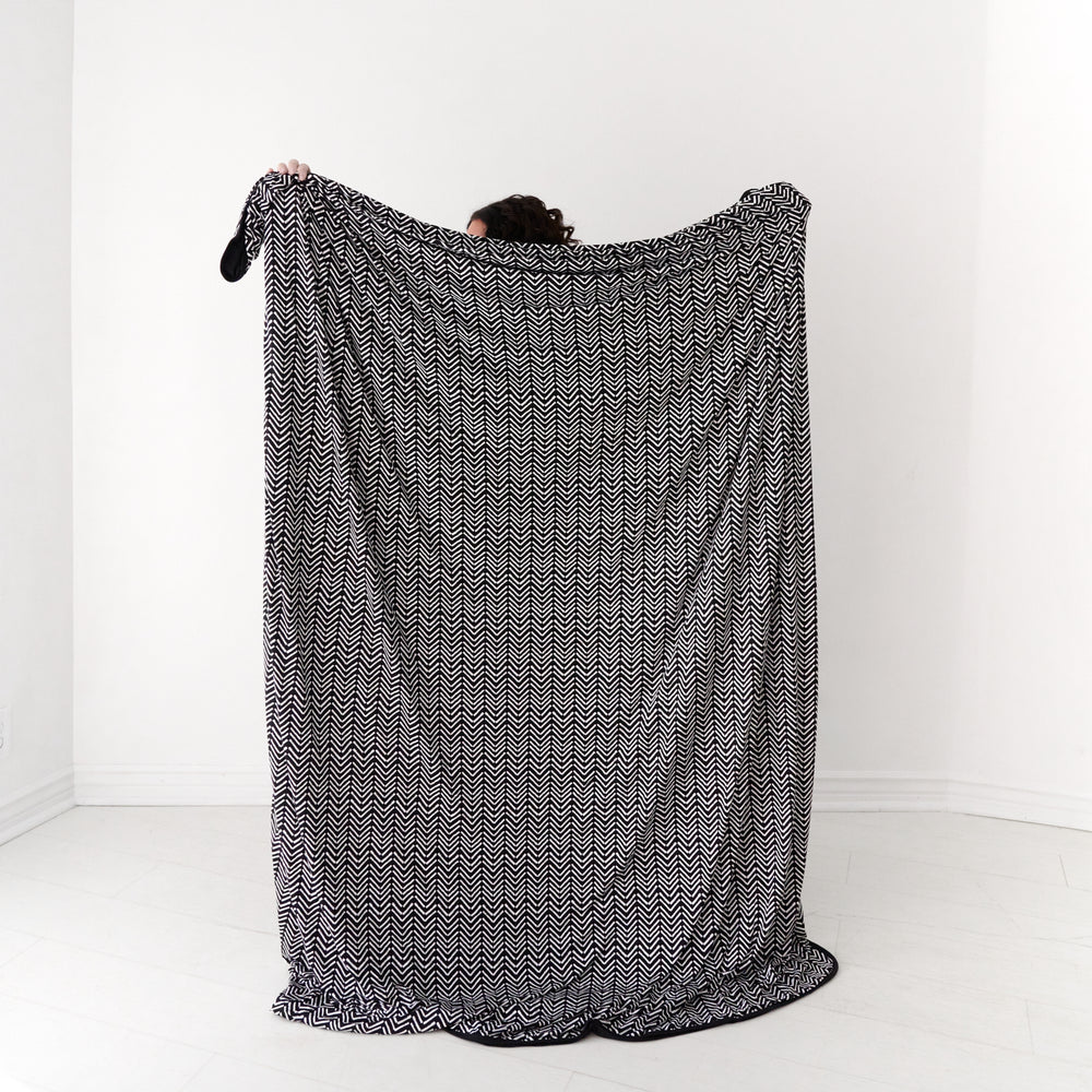 Back view image of a woman holding out a Monochrome Chevron oversized cloud blanket