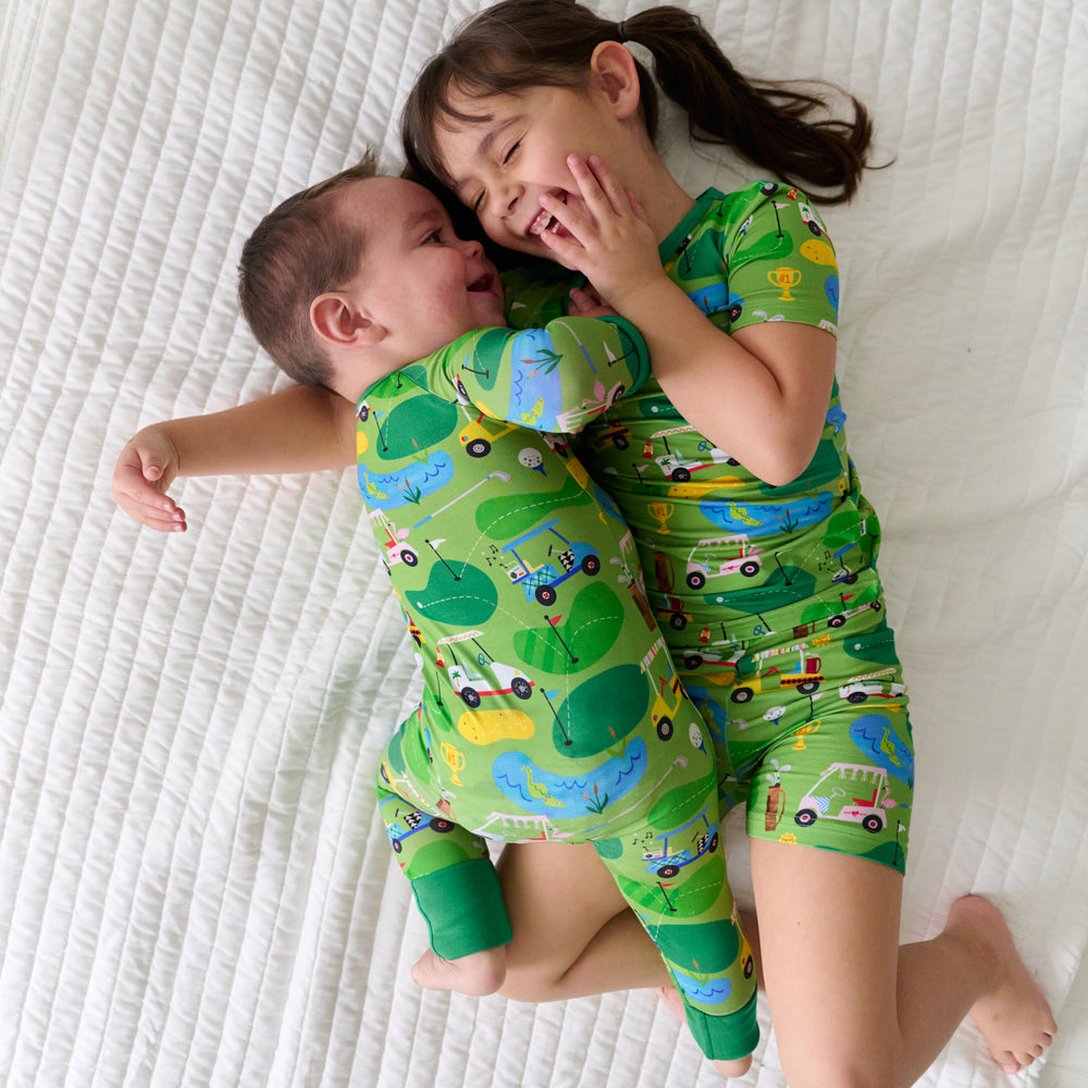 Two children laying on a blanket wearing matching Fairway Fun pajamas