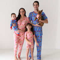 Family of four and their dog coordinating in All Stars printed pajama sets. Dad is wearing men's Blue All Stars pajama pants and matching men's pajama top. Mom is wearing women's pink All Stars pajama pants and matching women's pajama top. Kids are wearing Pink All Stars two piece short sleeve and shorts pajama set and a Blue All Stars zippy. Their dog is matching wearing a Pink All Stars pet bandana