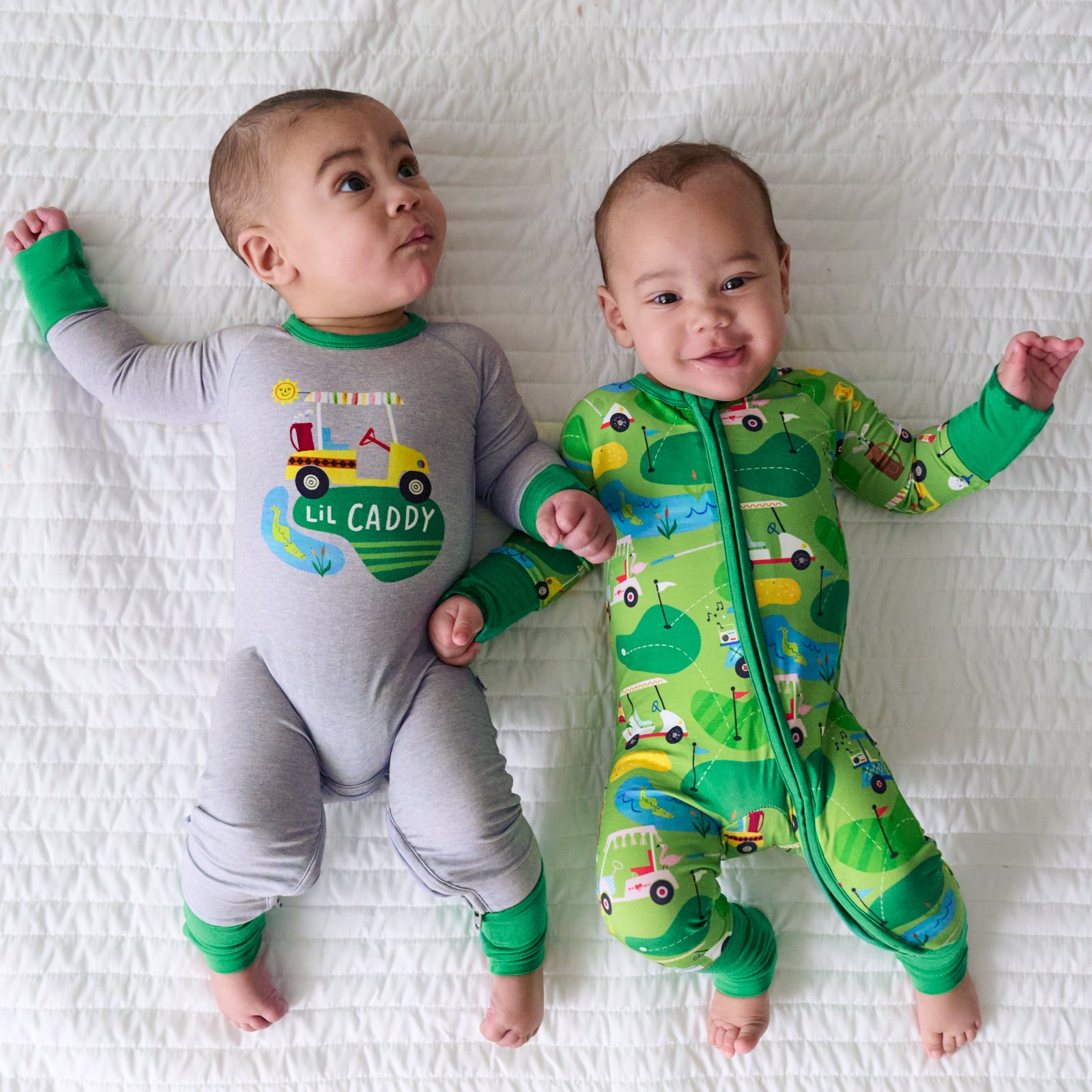 Two children laying on a blanket wearing coordinating Fairway Fun zippy and crescent zippy