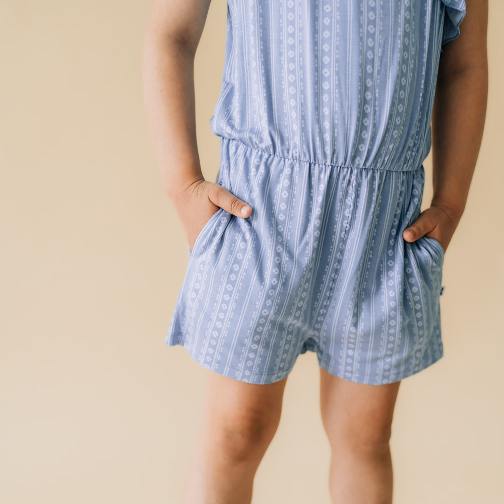 Close up image of a child wearing an Island stripe asymmetrical romper detailing the shorts pockets