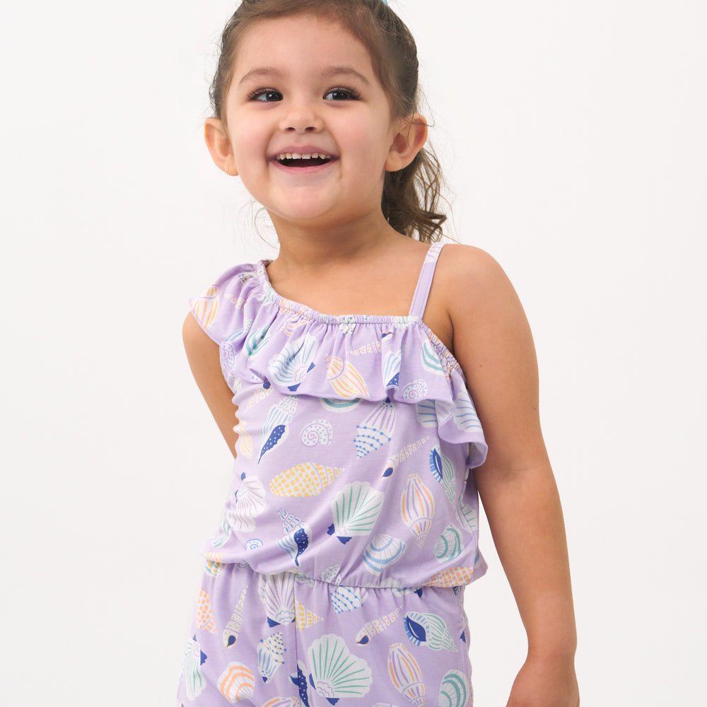 Close up image of a child posing wearing a Sandy Treasures Asymmetrical romper