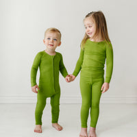 Two children holding hands wearing matching Avocado pajamas in zippy and two piece styles