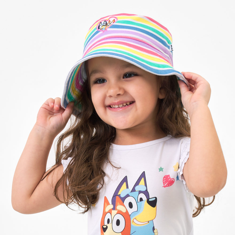 Close up image of a child wearing a Bluey rainbow bucket hat and coordinating top