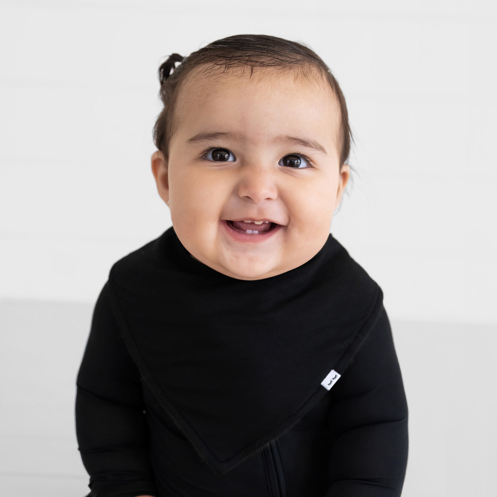 Close up image of a child wearing a Black bandana bib over a black zippy