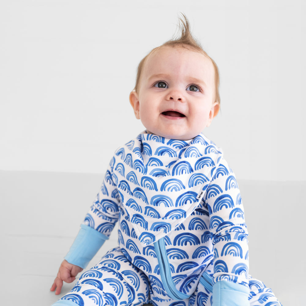 image of a child wearing a Blue Rainbows bandana bib over a matching blue rainbows zippy