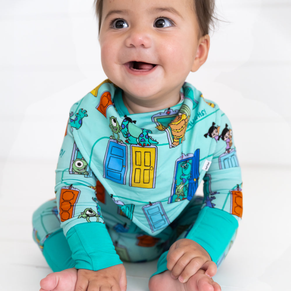 Additional close up image of baby sitting while wearing the Disney Monsters, Inc. Scream Team Bandana Bib and Disney Monsters, Inc. Scream Team Zippy