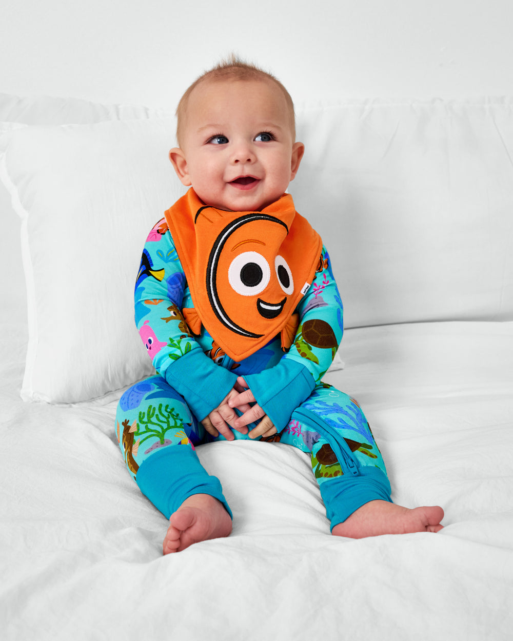 Sitting child wearing the Disney Nemo Bandana Bib with the Nemo's Reef zippy