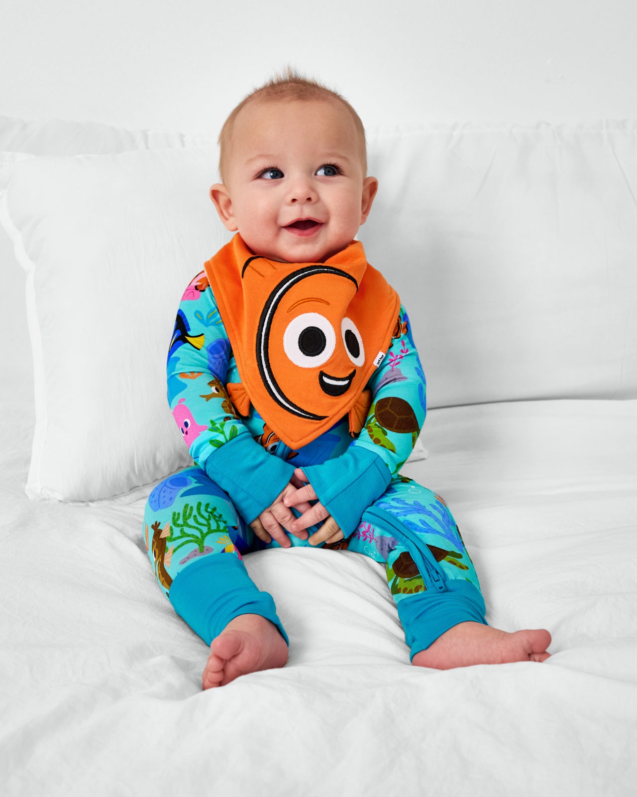 Sitting child wearing the Disney Nemo Bandana Bib with the Nemo's Reef zippy