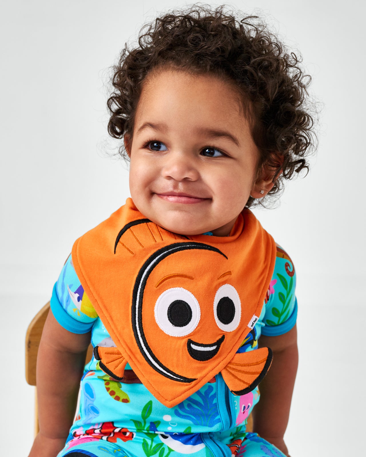 Sitting child wearing the Disney Nemo Bandana Bib and matching bamboo zippy