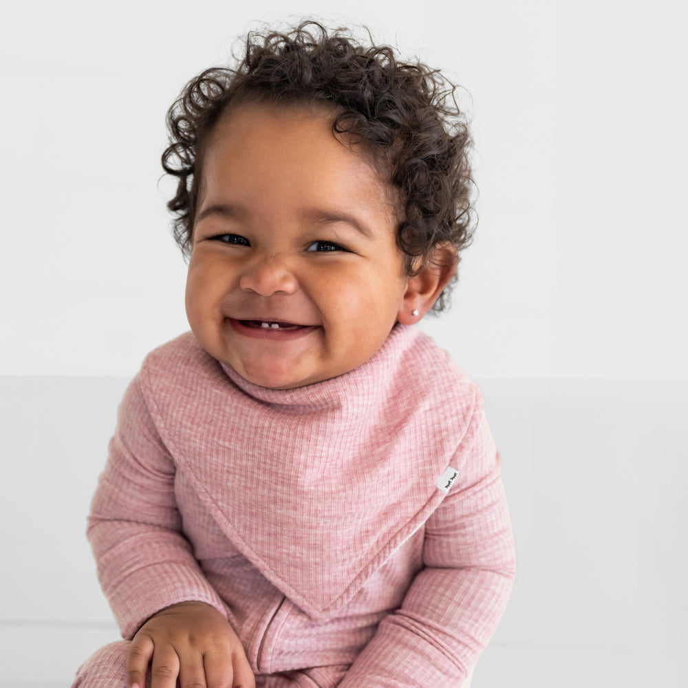 Close up image of a child wearing a Heather Mauve ribbed bandana bib over a matching Heather Mauve Ribbed zippy