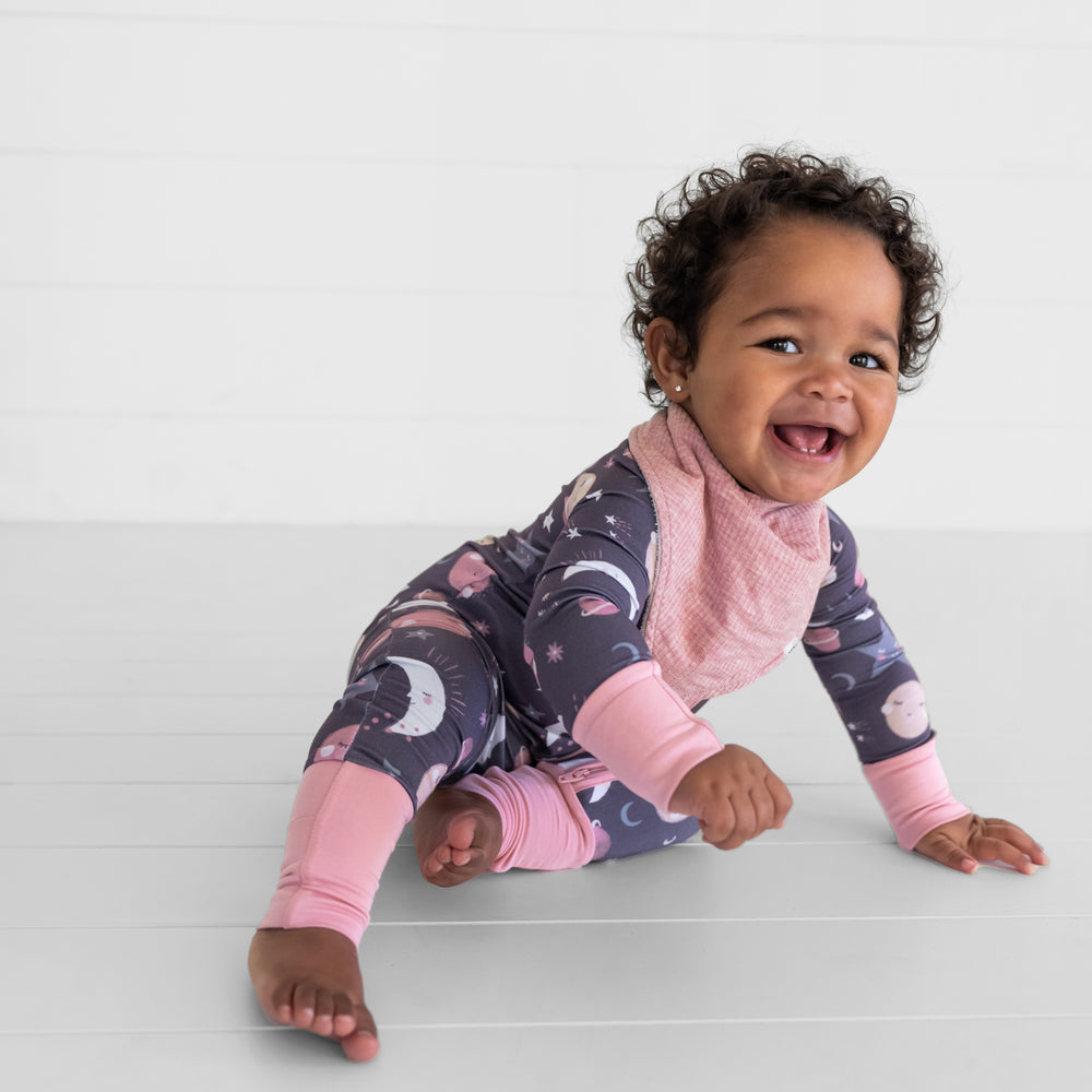 image of a child wearing a Heather Mauve ribbed bandana bib over a pink To the Moon and Back zippy