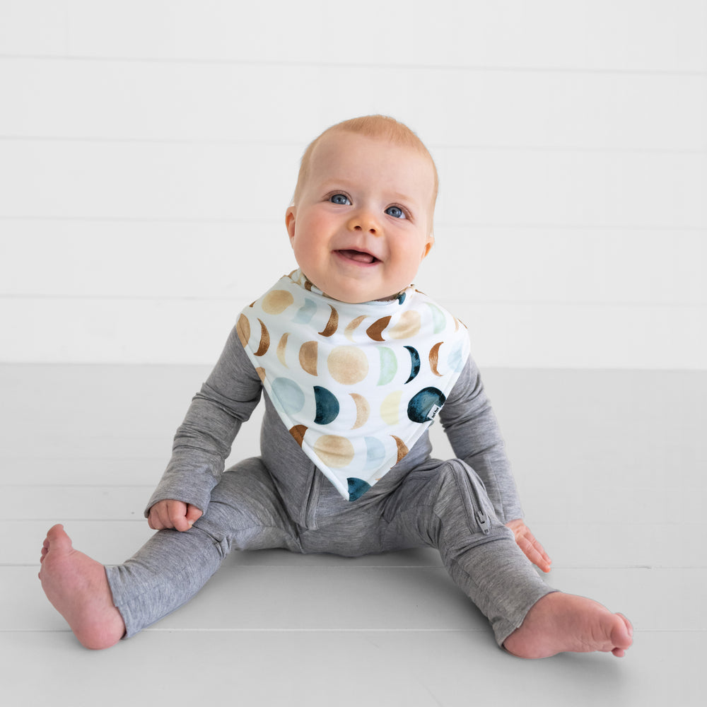 Image of a child wearing a Luna Neutral bandana bib over a heather gray zippy