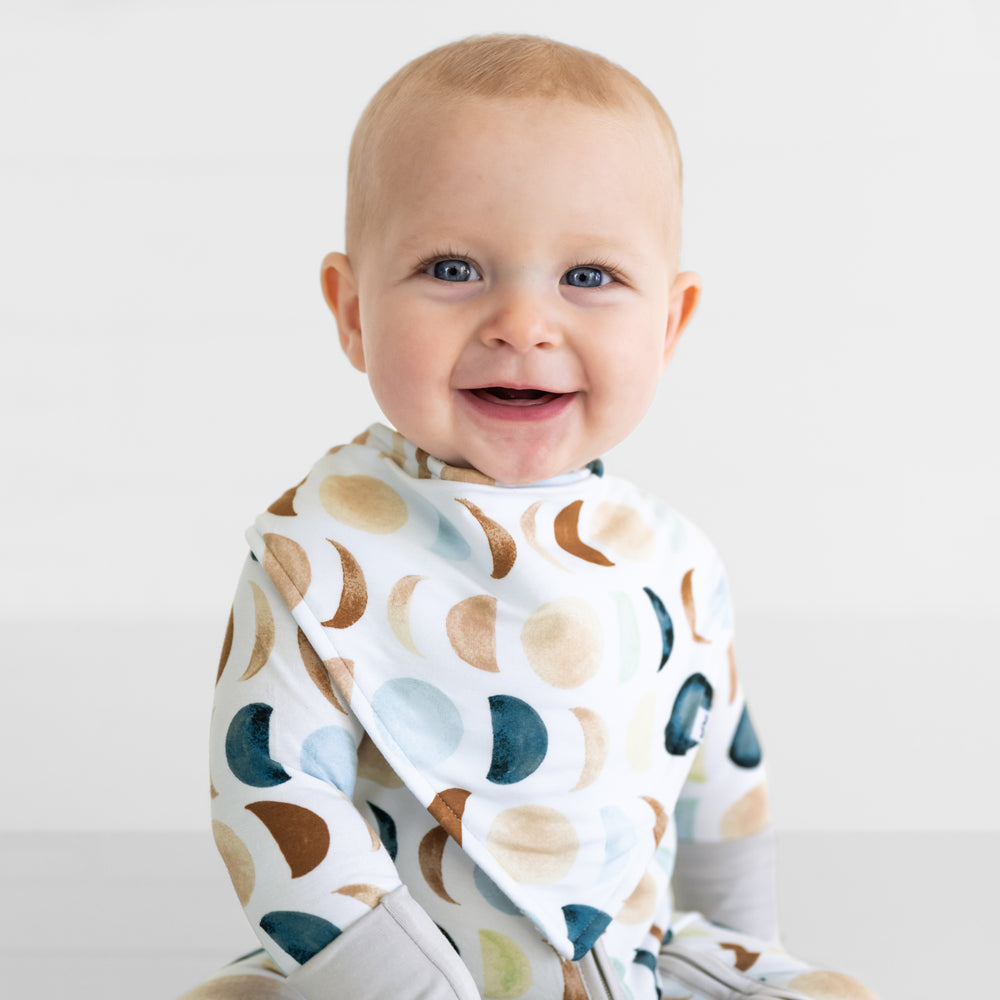 Close up of a child wearing a Luna Neutral bandana bib over a matching zippy