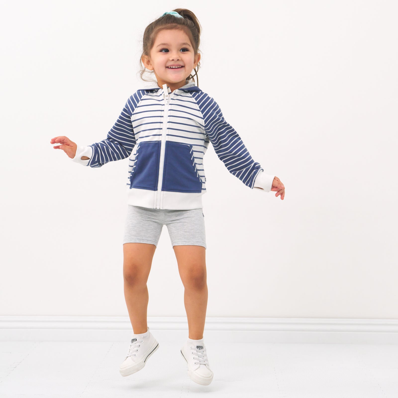 Child wearing Light Heather Gray bike shorts and coordinating zip hoodie