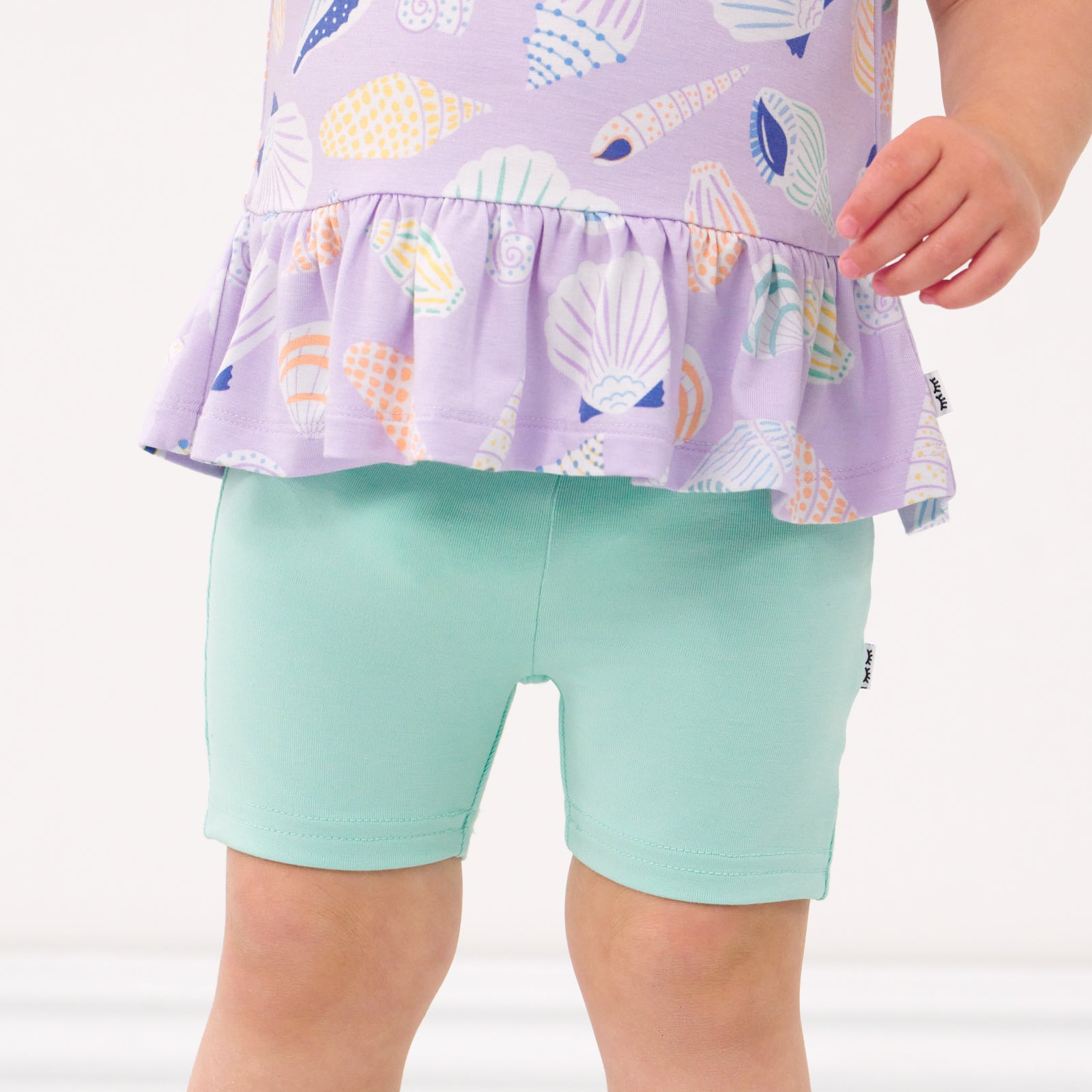 Close up image of a child wearing Ocean Waves bike shorts and coordinating Play top