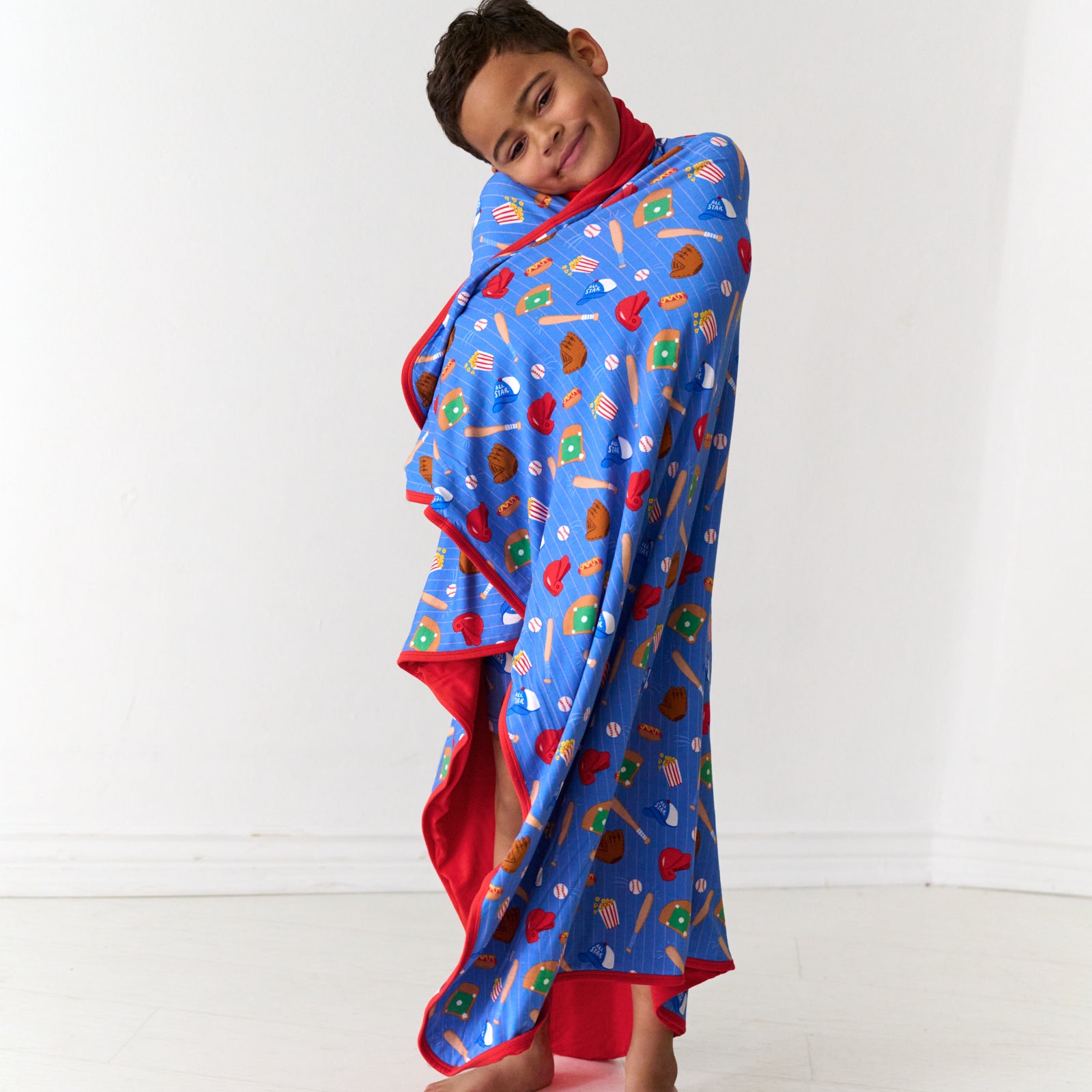 Child wrapped up wearing a Blue All Stars printed large cloud blanket