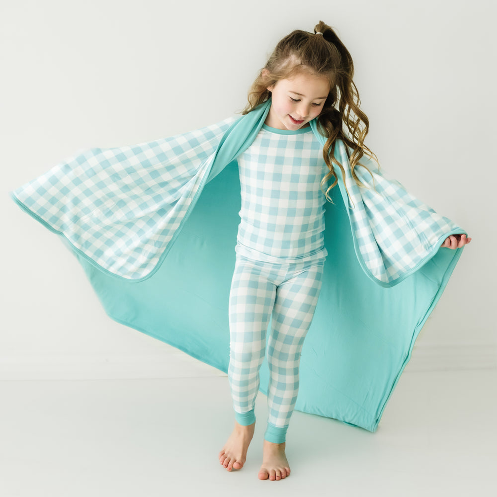 Click to see full screen - Child wearing a Aqua Gingham cloud blanket over her shoulders and a matching aqua gingham two piece pajama set