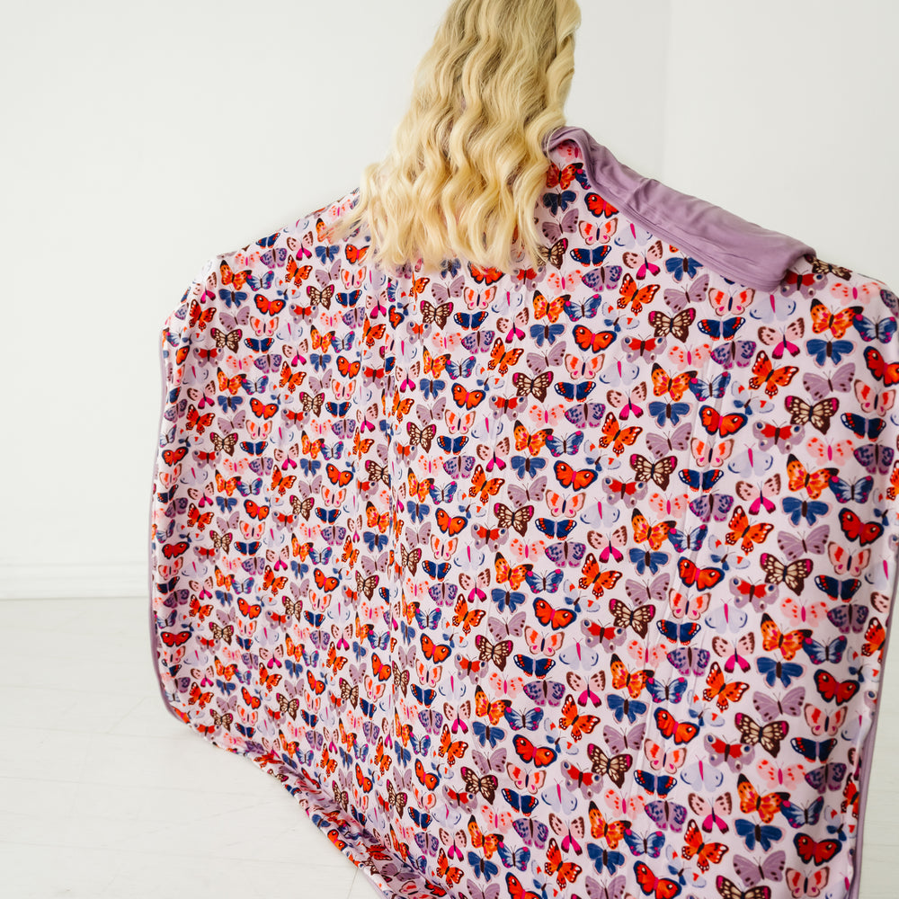 Back view image of a child holding out a Butterfly Kisses large cloud blanket