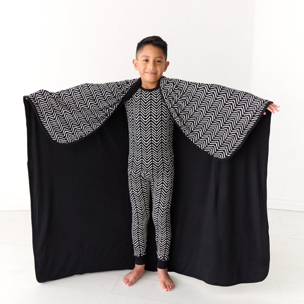 Child holding out a Monochrome Chevron large cloud blanket detailing the solid colored backing