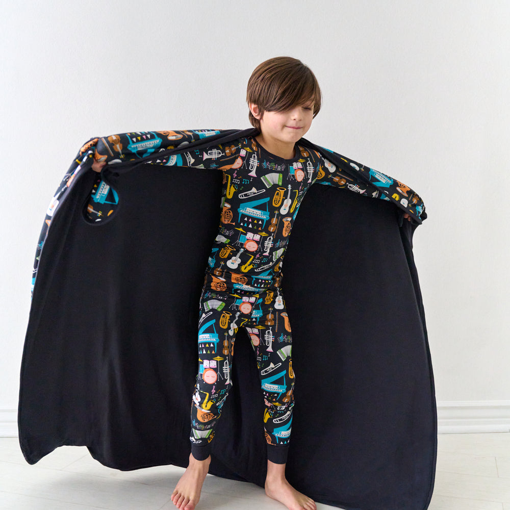 Child holding out a Keys and Chords large cloud blanket behind them detailing the solid backing and wearing matching pajamas