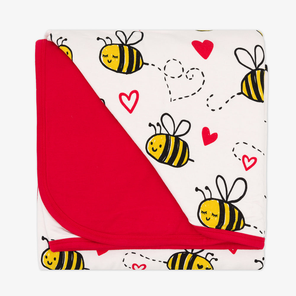 Flat lay image of a Bee Mine Blanket showing the solid red backing