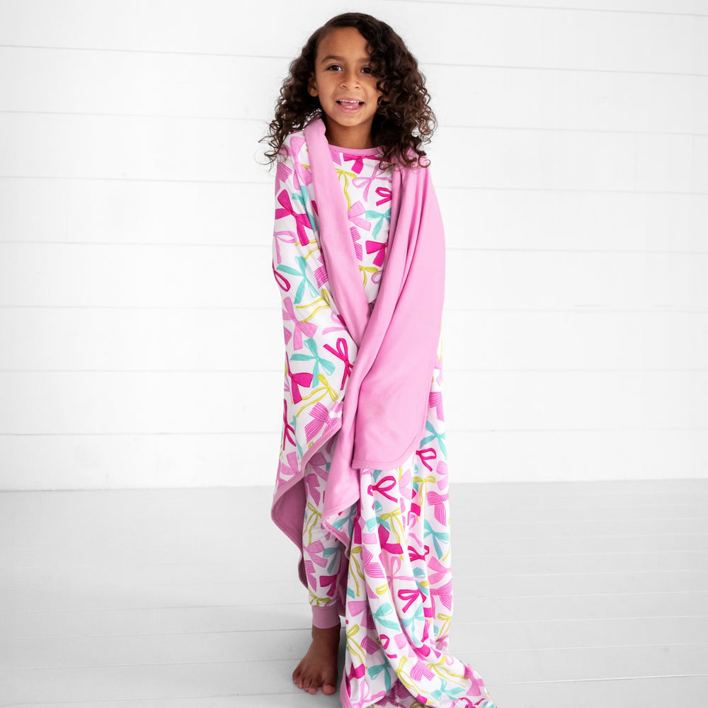 Image of a child wrapped in a ribbons and bows large cloud blanket