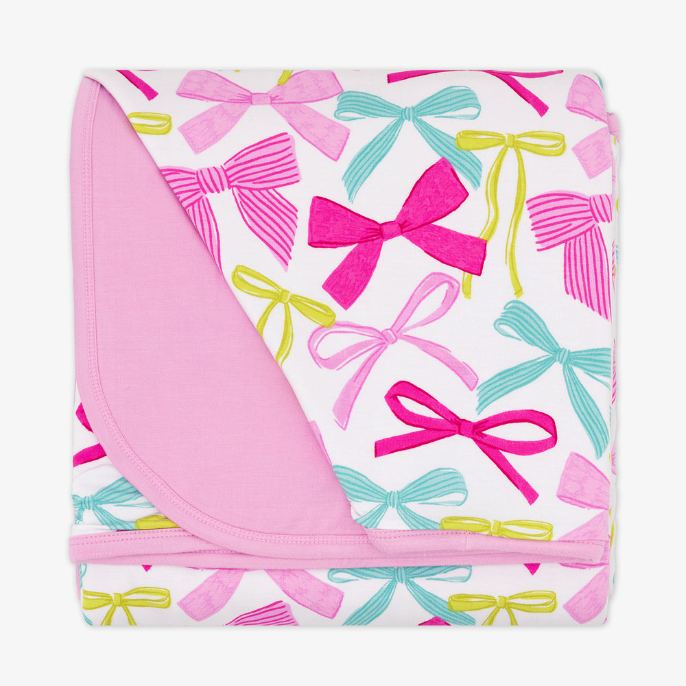 flat lay image of a Ribbons and Bows large cloud blanket showing the pink backing