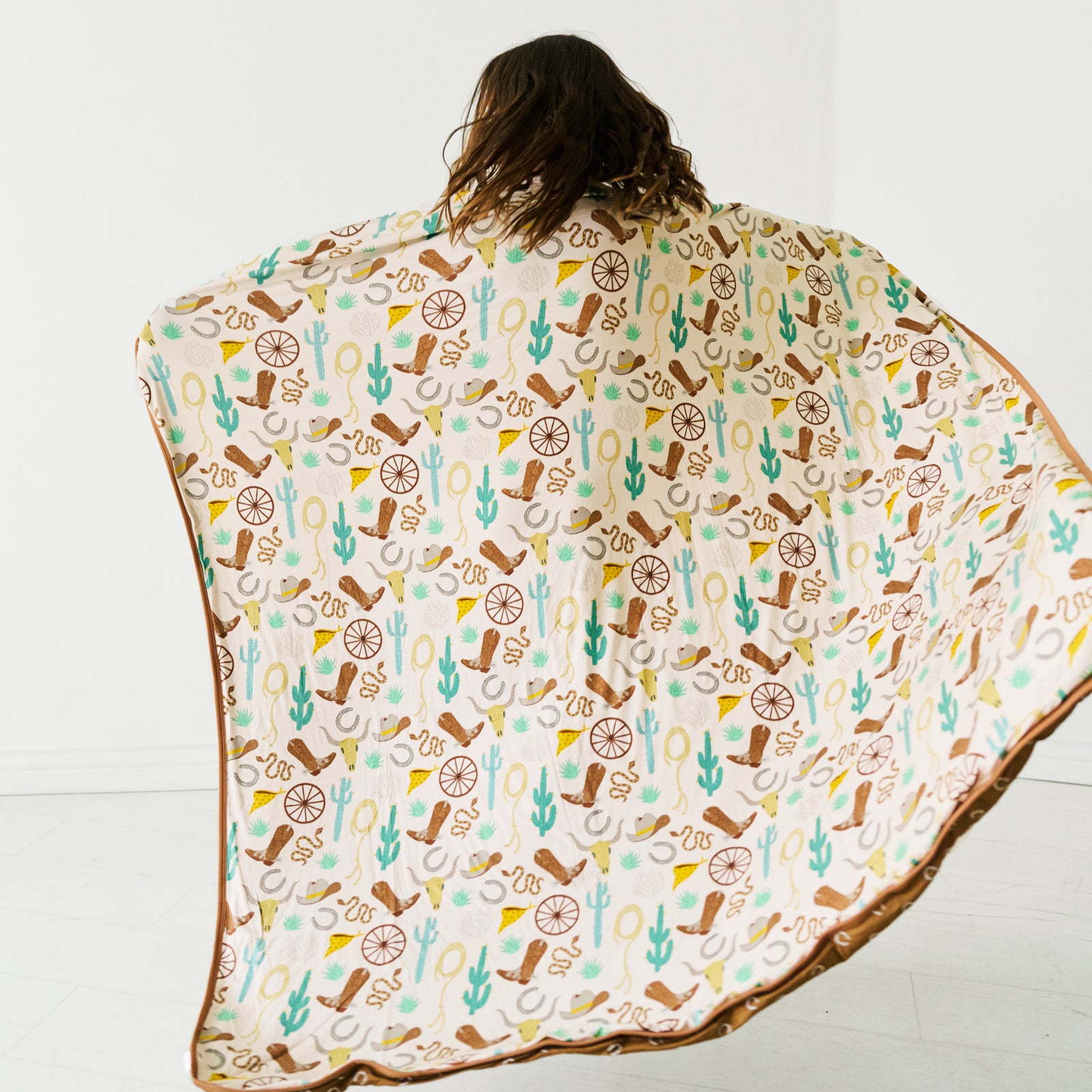 Back side view of a child holding up in a Caramel Ready to Rodeo large cloud blanket 