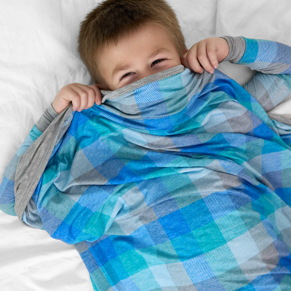 image of a child tucked under an Arctic Plaid cloud blanket