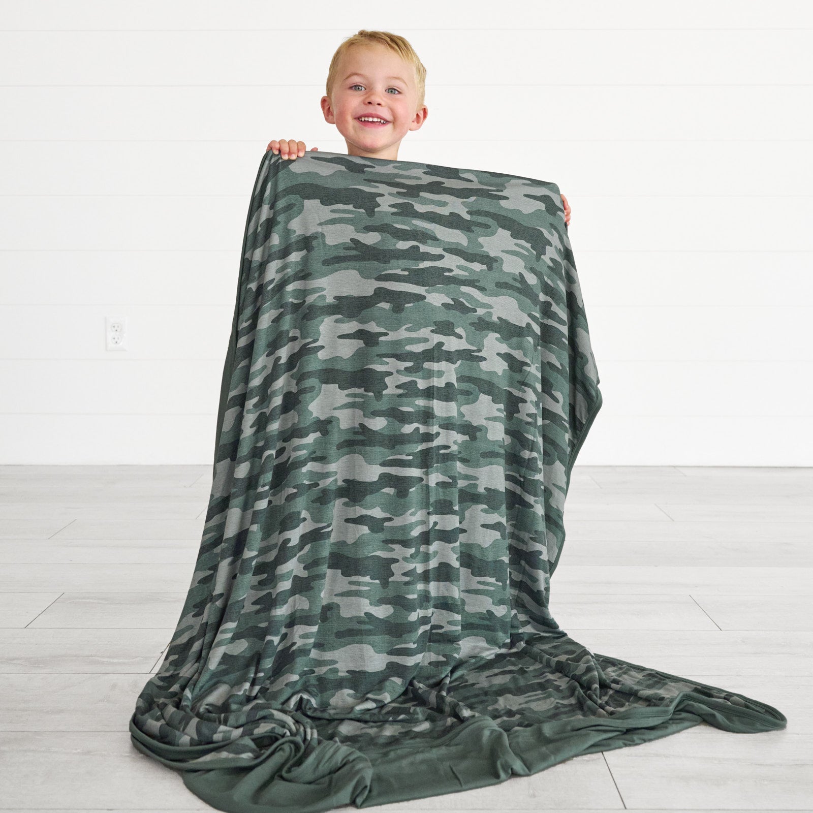 Alternative image of boy posing with the Vintage Camo Large Cloud Blanket® displaying the back camo detail