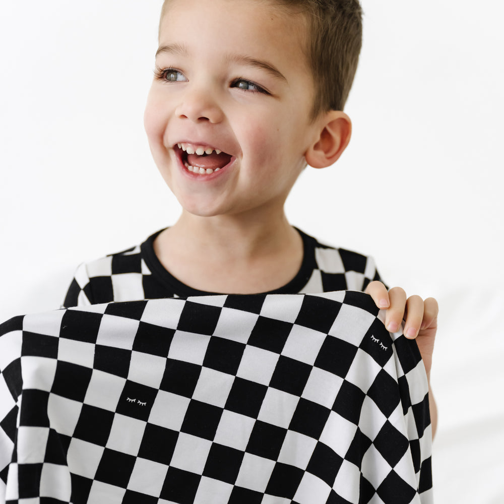 close up image of a child holding up a Cool Checks cloud blanket