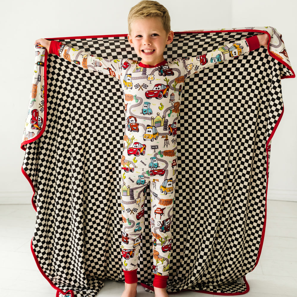 Child wearing a Radiator Springs two piece pajama set holding out a matching cloud blanket