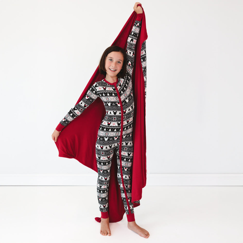 child holding up a Mickey Fair Isle blanket showing the solid red backing