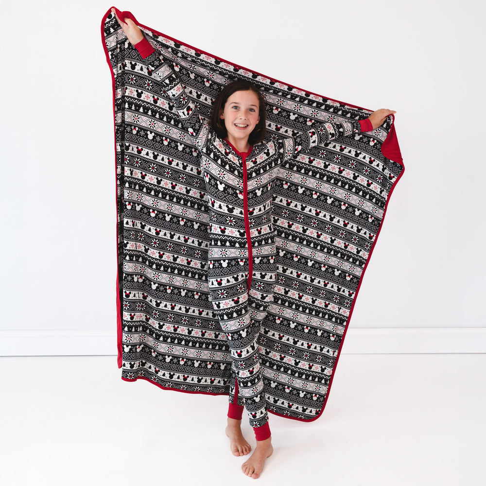 Child holding up a Mickey Fair Isle blanket wearing a matching Mickey Fair Isle zippy