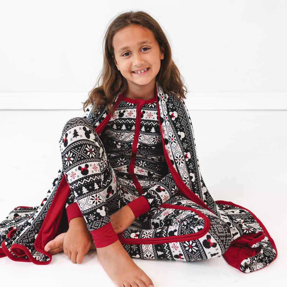 child sitting wrapped up in a Mickey Fair isle cloud blanket and matching zippy