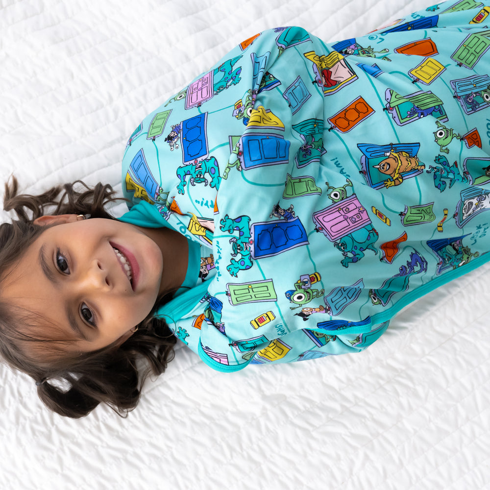 Top view image of smiling girl wrapped in the Disney Monsters, Inc. Scream Team Large Cloud Blanket®