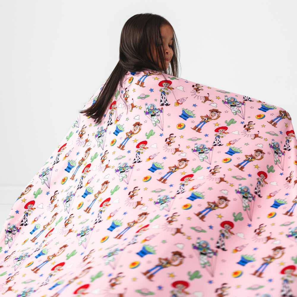 Image of a child twirling holding up a Pink Toy Story Stars cloud blanket